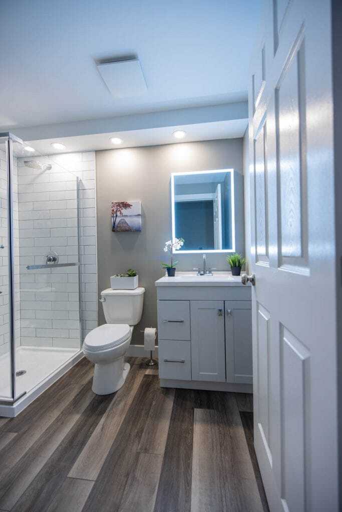 white vanity with vinyl click flooring basement bathroom
